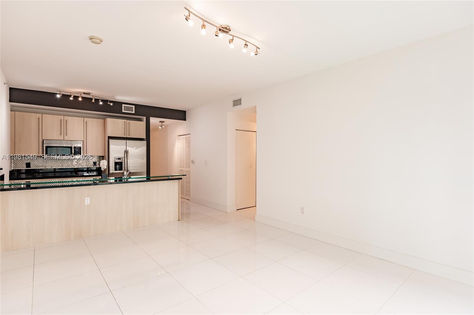 A kitchen with light wood cabinets and a glass-topped breakfast bar opens to a living area — 1111 SW 1st Ave, Miami FL 33130, MIAMI, FL
