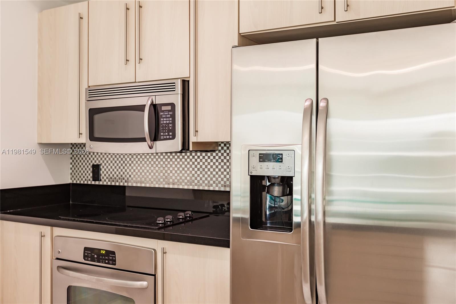 A kitchen features light wood cabinets, stainless steel appliances, and a black countertop — 1111 SW 1st Ave, Miami FL 33130, MIAMI, FL