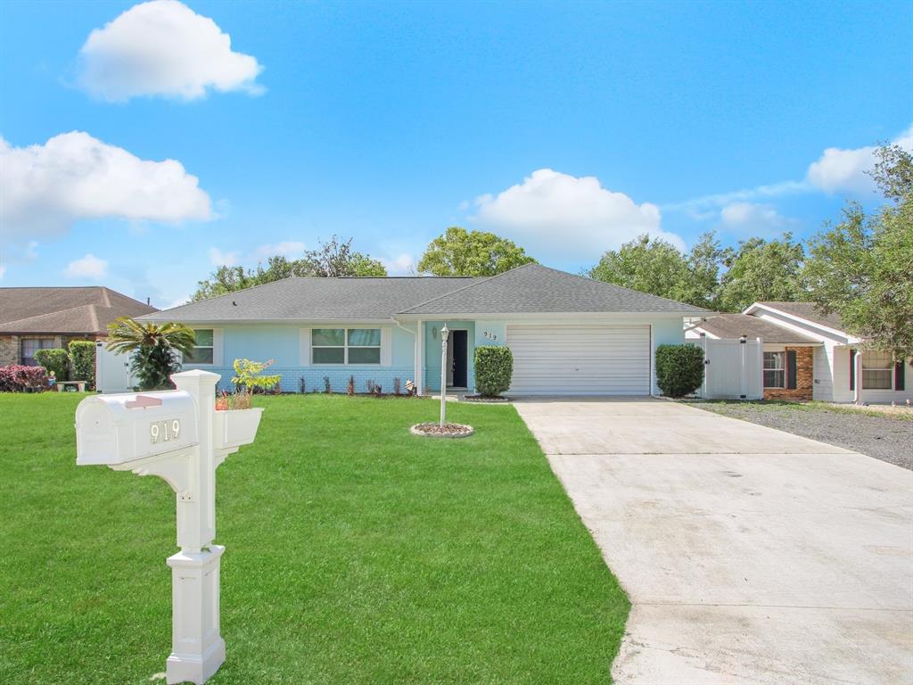 A single-story house with a light-colored exterior, a two-car garage, and a sunset sky — 919 SYLVIA DRIVE, DELTONA, FL