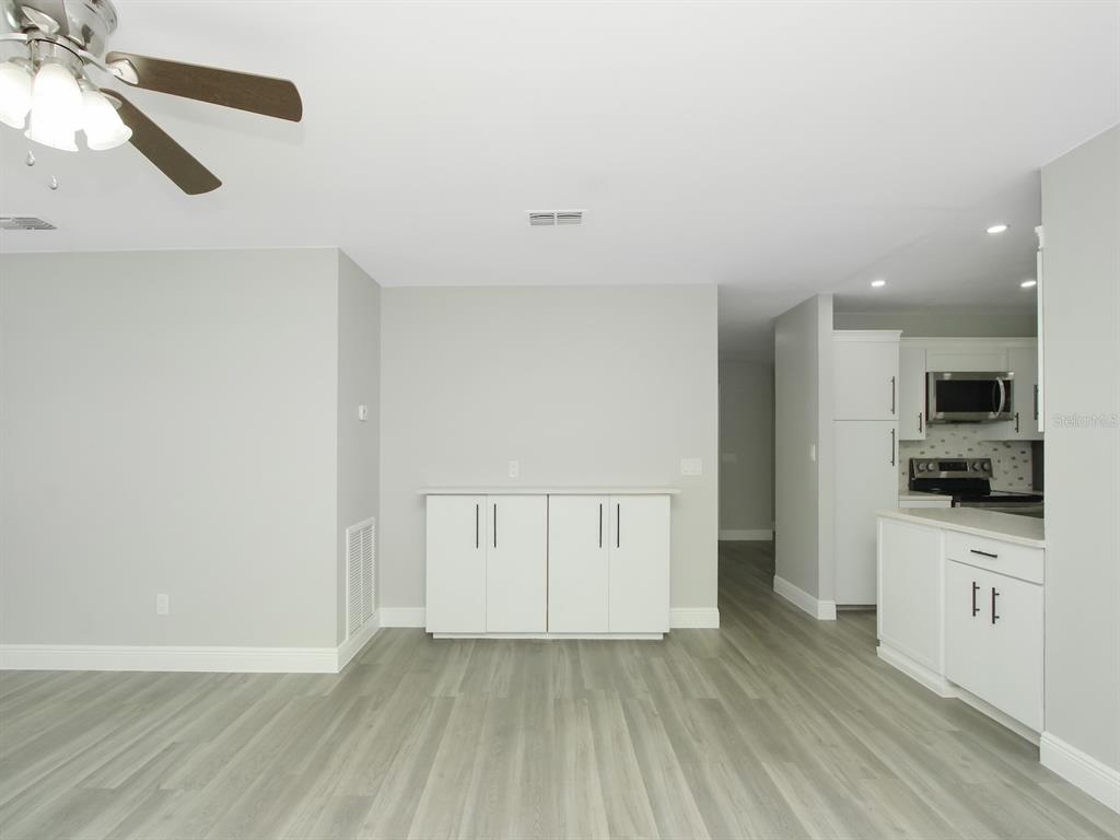 A room with light gray walls, wood-look flooring, a ceiling fan, and white cabinetry — 919 SYLVIA DRIVE, DELTONA, FL