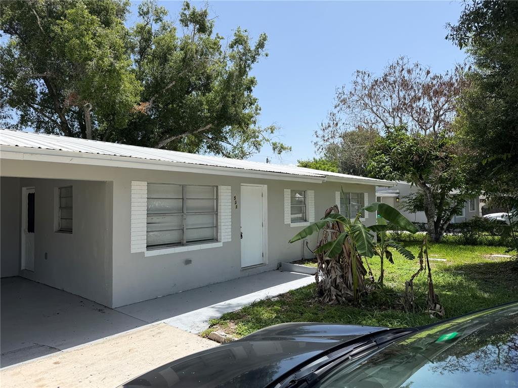 A single-story house with a white metal roof, gray exterior, and a carport — 1531 NE 14TH STREET, OKEECHOBEE, FL