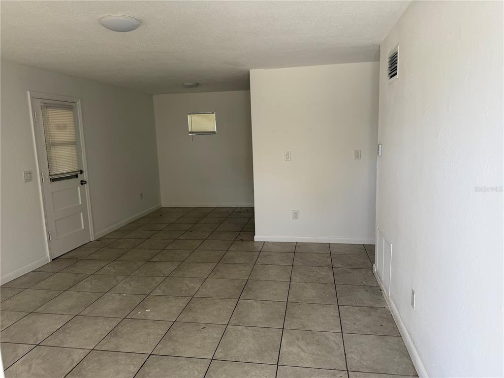 An empty room with white walls, tile flooring, and a door leading outside — 1531 NE 14TH STREET, OKEECHOBEE, FL