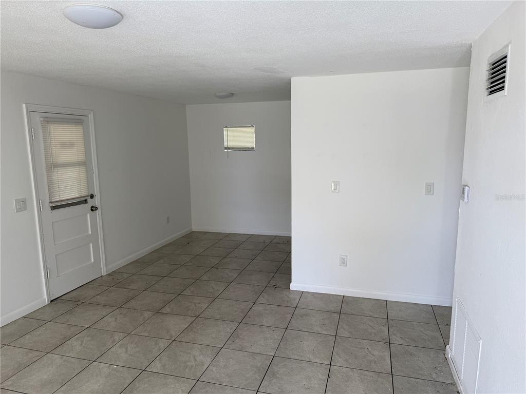 An interior room with white walls, tile flooring, a door, and a small window — 1531 NE 14TH STREET, OKEECHOBEE, FL