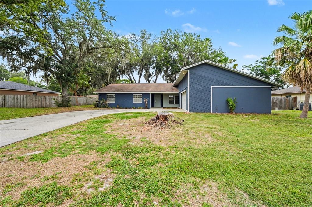 A blue single-story house with a driveway and a large tree stump in the yard — 1234 FAIRFAX N, LAKELAND, FL