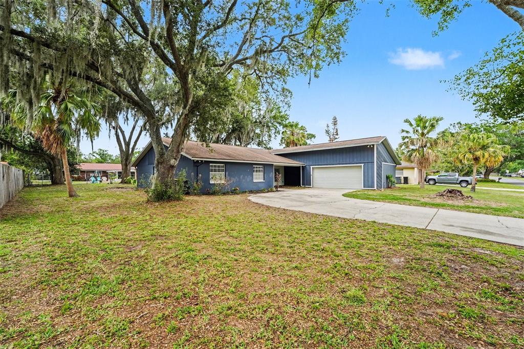 A blue single-story house with a two-car garage and a large front yard with trees — 1234 FAIRFAX N, LAKELAND, FL