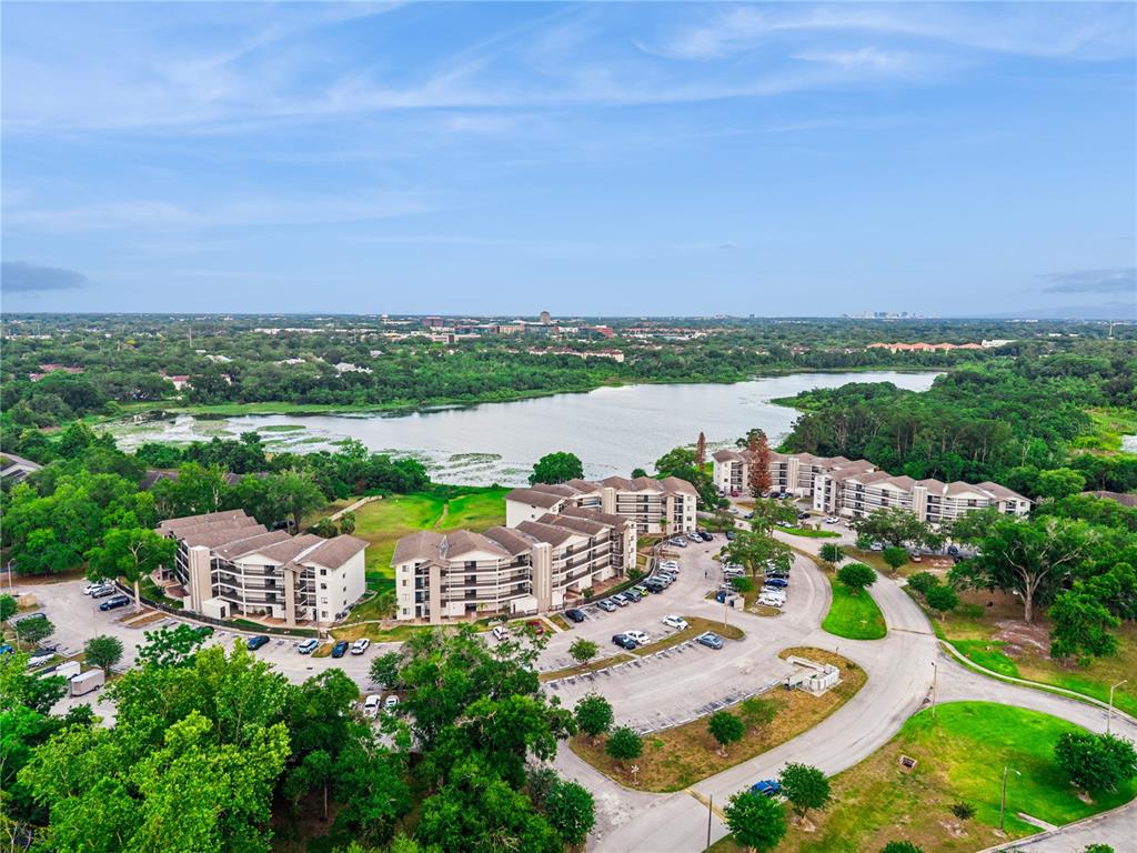 An aerial view shows apartment buildings situated near a lake surrounded by trees — 1068 LOTUS PARKWAY UNIT 834, ALTAMONTE SPRINGS, FL