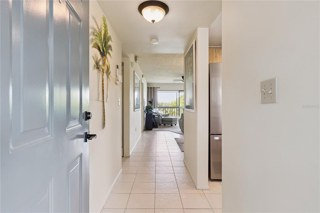An entryway with tiled flooring leads down a hallway toward a living area with balcony — 1068 LOTUS PARKWAY UNIT 834, ALTAMONTE SPRINGS, FL