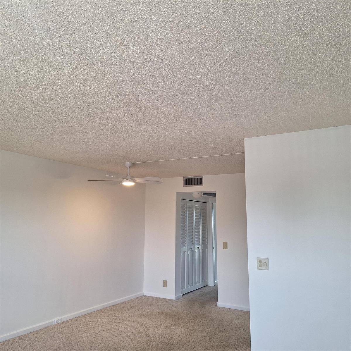 An empty room with beige carpet, a popcorn ceiling, and a white ceiling fan — 4007 Cornwall A # 4007, Boca Raton FL 33434, BOCA RATON, FL