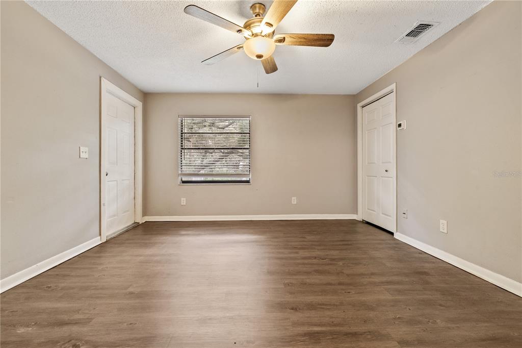 An empty room with wood-look flooring, a ceiling fan, a window, and two white doors — 1221 E MOHAWK AVENUE UNIT C, TAMPA, FL