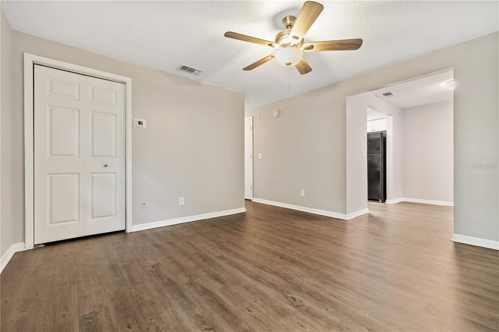 A living room with light gray walls, wood-look flooring, a ceiling fan, and a closet — 1221 E MOHAWK AVENUE UNIT C, TAMPA, FL
