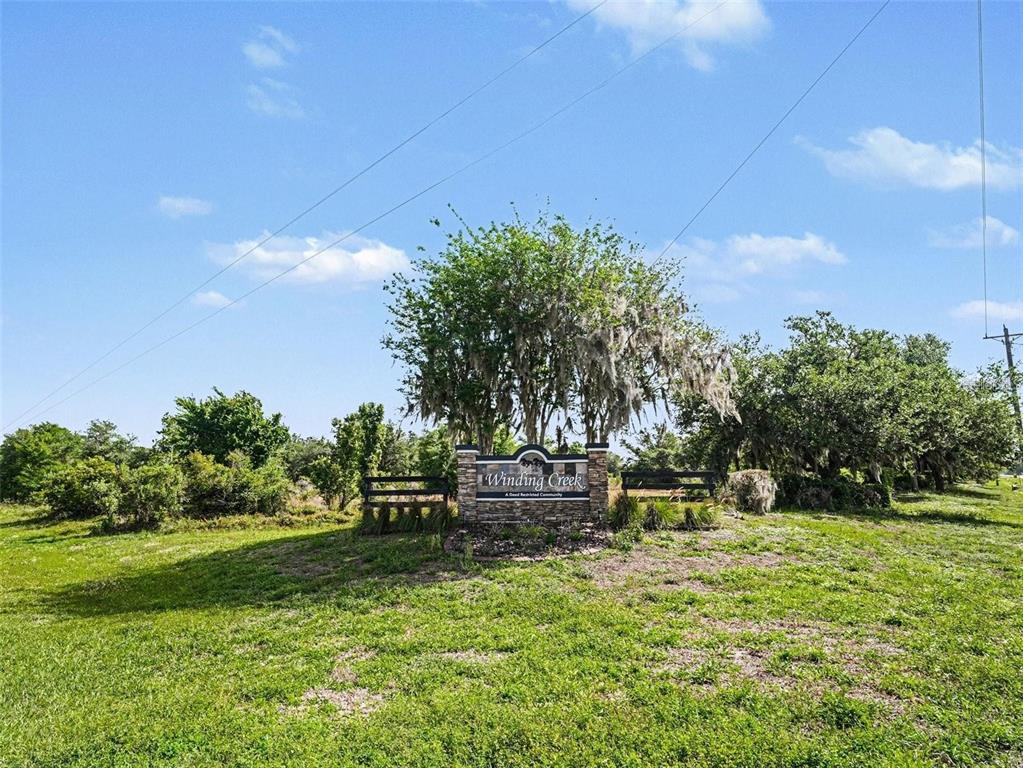 A stone sign for Winding Creek community stands in a grassy field under a tree — 41155 STATE RD 64 EAST, MYAKKA CITY, FL