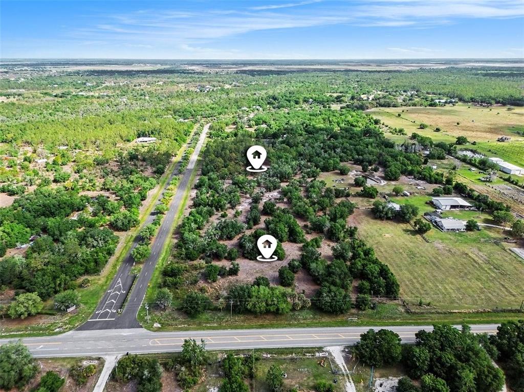 An aerial view shows a wooded plot of land adjacent to a paved road — 41155 STATE RD 64 EAST, MYAKKA CITY, FL