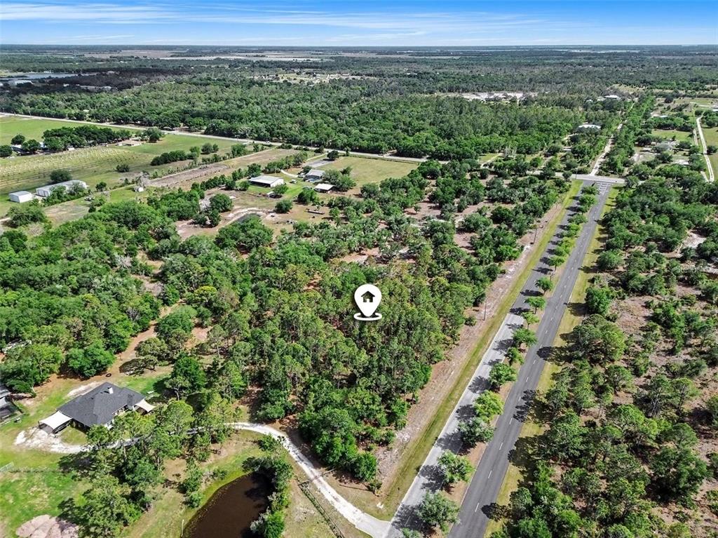 An aerial view shows a wooded lot with a location pin next to a road — 41155 STATE RD 64 EAST, MYAKKA CITY, FL