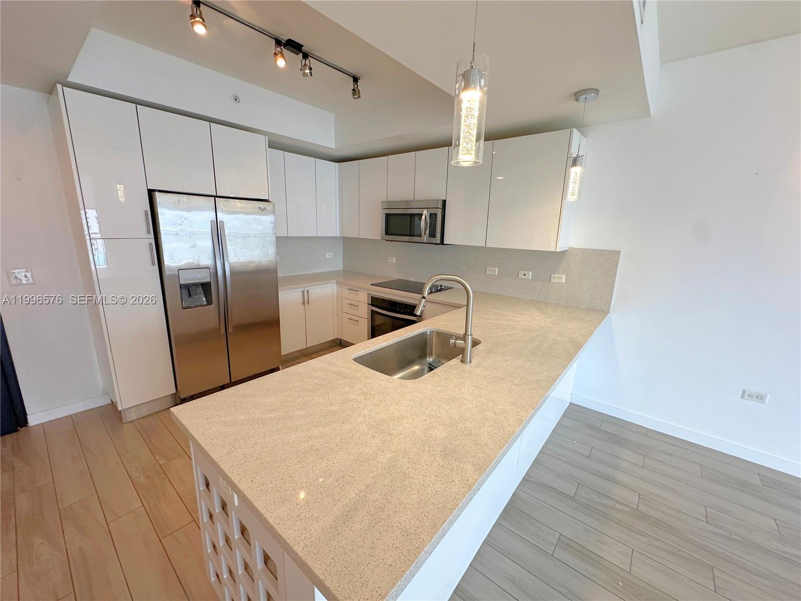 A modern kitchen features white cabinets, stainless steel appliances, and a large quartz island — 999 SW 1st Ave # 2109, Miami FL 33130, MIAMI, FL