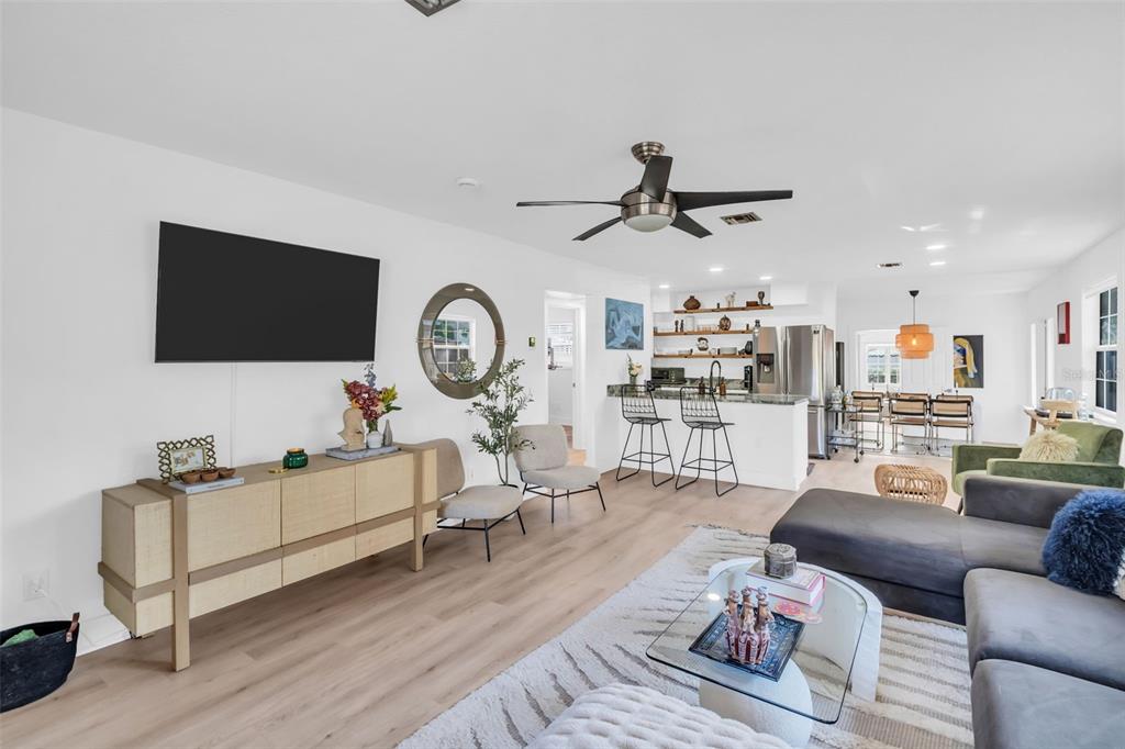 A bright, open-concept living room and kitchen featuring light wood flooring and modern furnishings — 218 49TH AVENUE N, ST PETERSBURG, FL