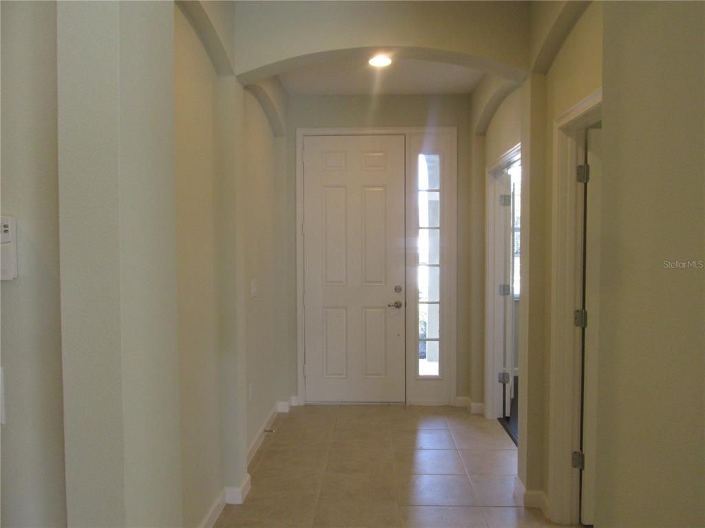 An entryway features a white front door with a sidelight, tiled floors, and arched ceiling — 2404 SABASTIAN STREET, MOUNT DORA, FL
