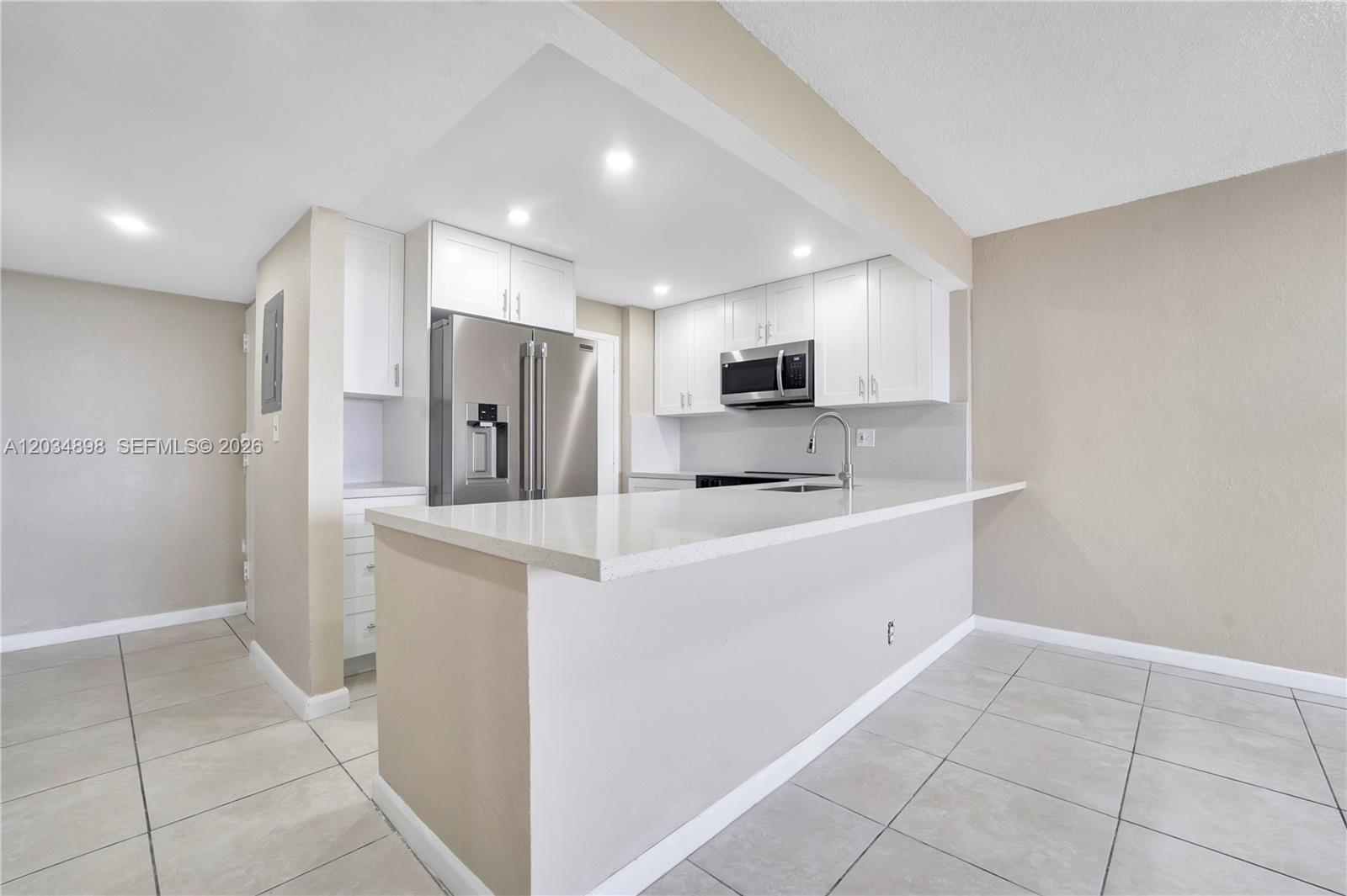 A kitchen features white cabinets, stainless steel appliances, and a quartz breakfast bar — 9001 SW 77th Ave # C709, Miami FL 33156, MIAMI, FL