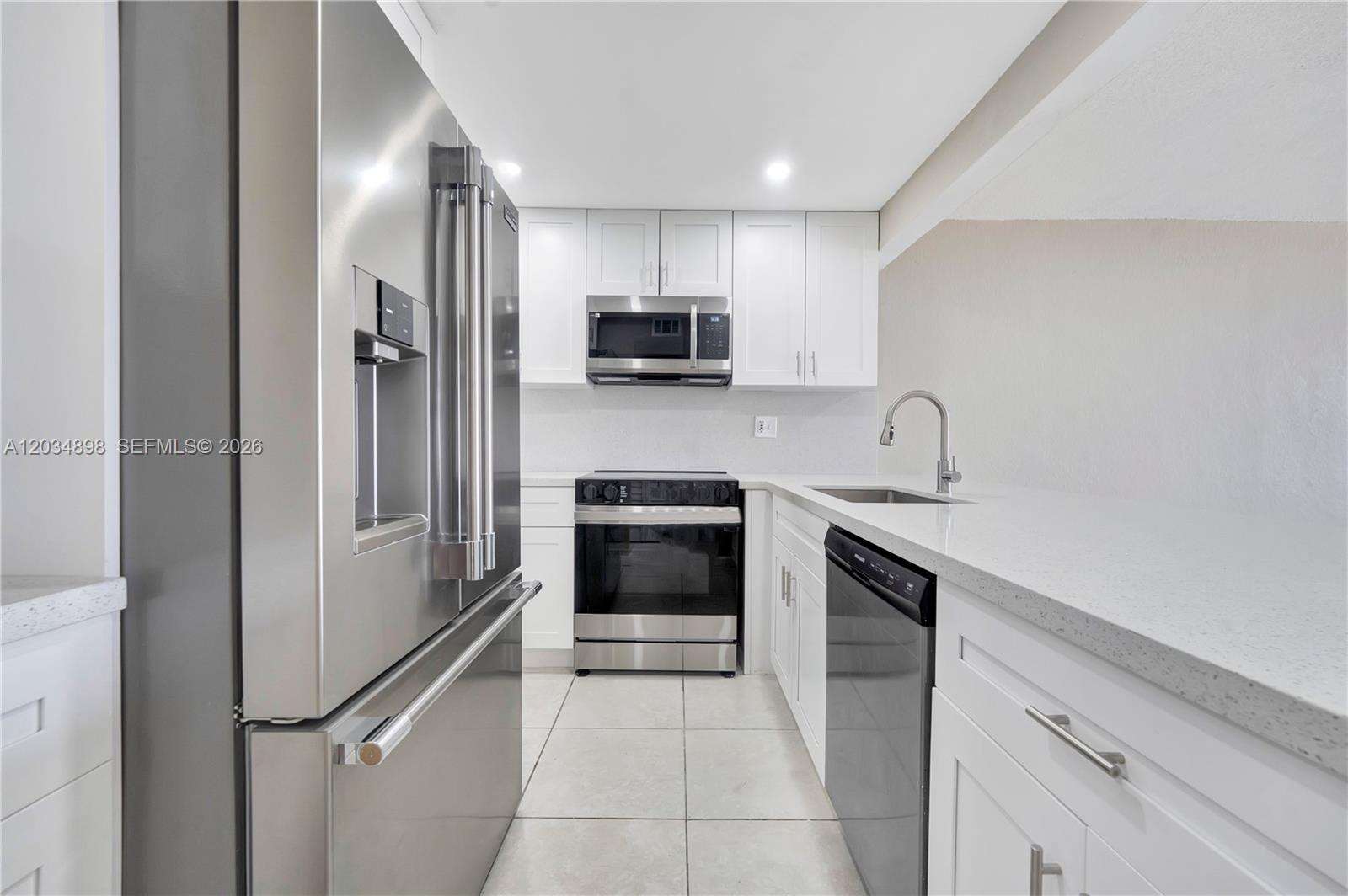 A modern kitchen features white cabinets, stainless steel appliances, and light-colored countertops — 9001 SW 77th Ave # C709, Miami FL 33156, MIAMI, FL