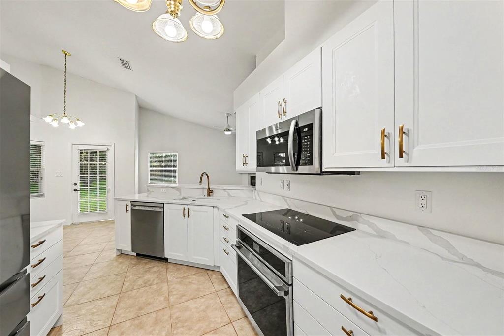 A modern kitchen features white cabinetry, stainless steel appliances, and white marble-patterned countertops — 19610 WYNDMILL CIRCLE, ODESSA, FL