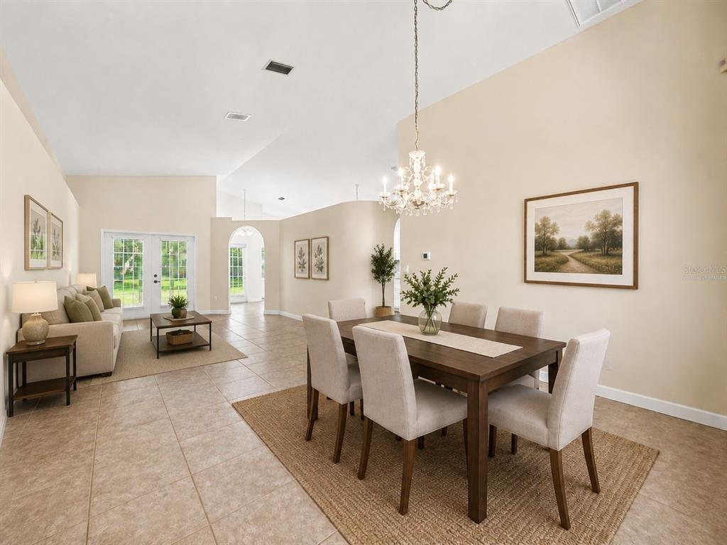 A dining area with a wooden table and chandelier sits adjacent to a living room — 19610 WYNDMILL CIRCLE, ODESSA, FL