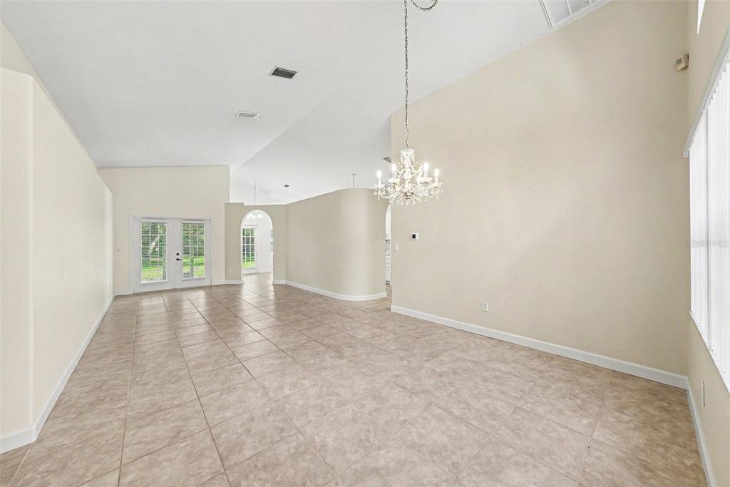 A spacious dining room features tile flooring, a crystal chandelier, and high vaulted ceilings — 19610 WYNDMILL CIRCLE, ODESSA, FL