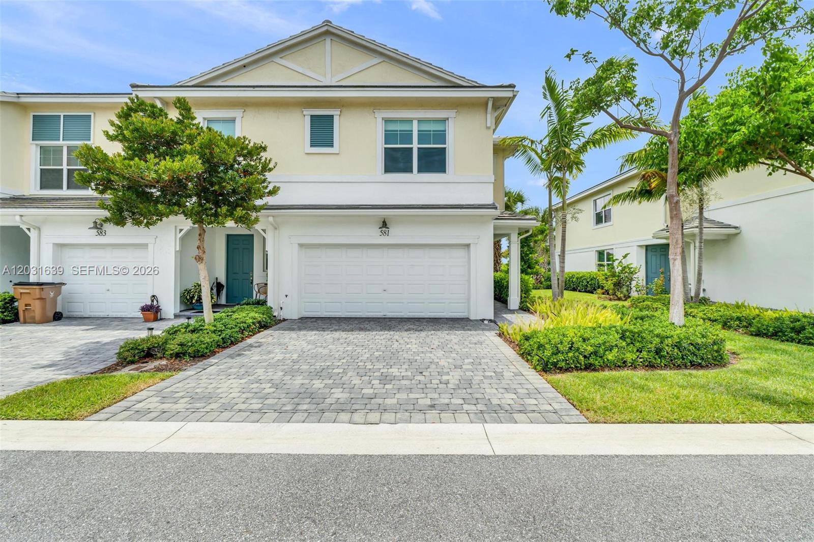A two-story townhouse features a white garage, a paved driveway, and a small front garden — 581 Sanderling Cir # 581, Deerfield Beach FL 33442, DEERFIELD BEACH, FL