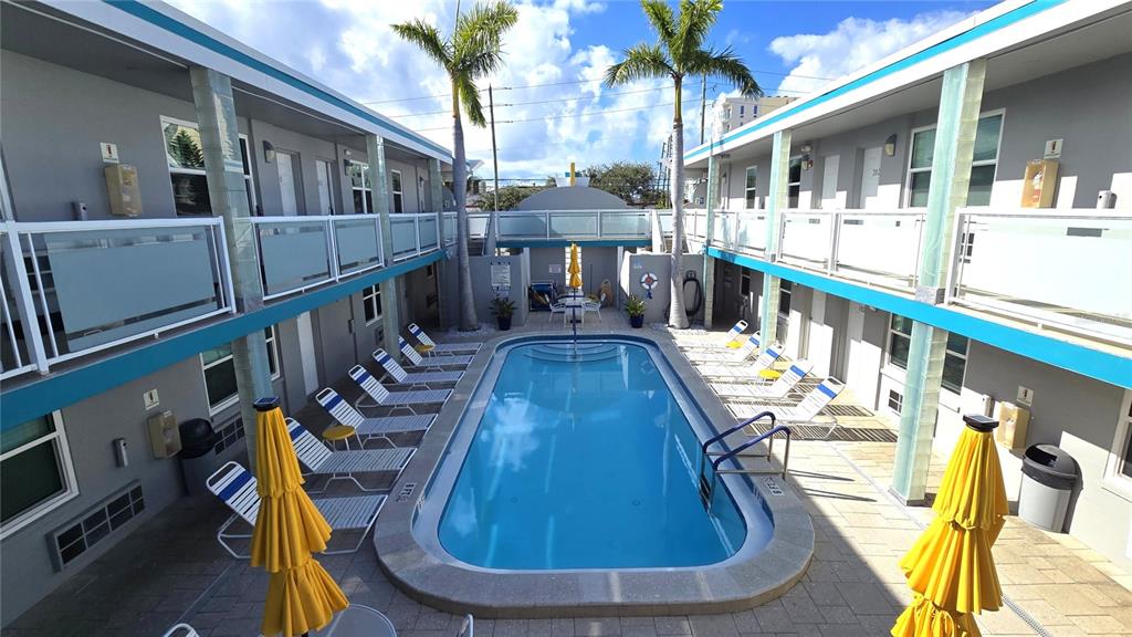 A rectangular swimming pool is centered in a courtyard between two levels of motel rooms — 603 MANDALAY AVENUE UNIT 207, CLEARWATER BEACH, FL