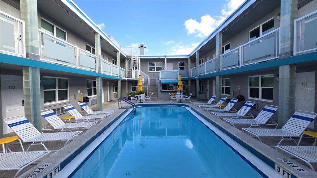 A rectangular swimming pool is centered in a courtyard surrounded by two-story motel units — 603 MANDALAY AVENUE UNIT 207, CLEARWATER BEACH, FL