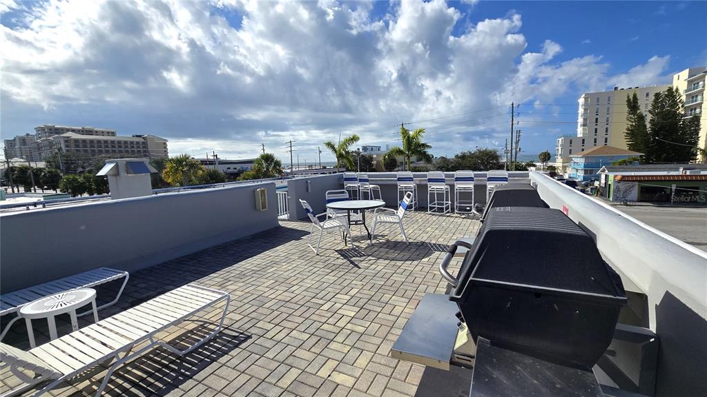 A rooftop patio features a brick-paved floor, outdoor seating, and a grill — 603 MANDALAY AVENUE UNIT 207, CLEARWATER BEACH, FL