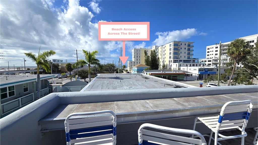 An elevated view from a balcony overlooking a street with beach access in the distance — 603 MANDALAY AVENUE UNIT 207, CLEARWATER BEACH, FL