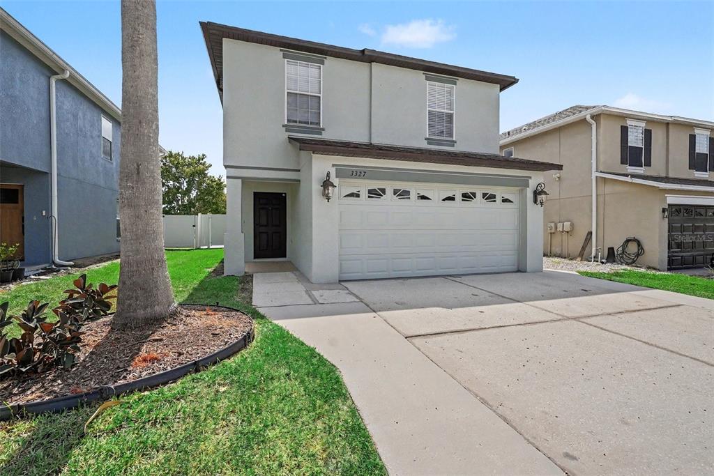 The rear exterior of a two-story house features a paved patio and a white fence — 3327 THISTLEDOWN LANE, LAND O LAKES, FL
