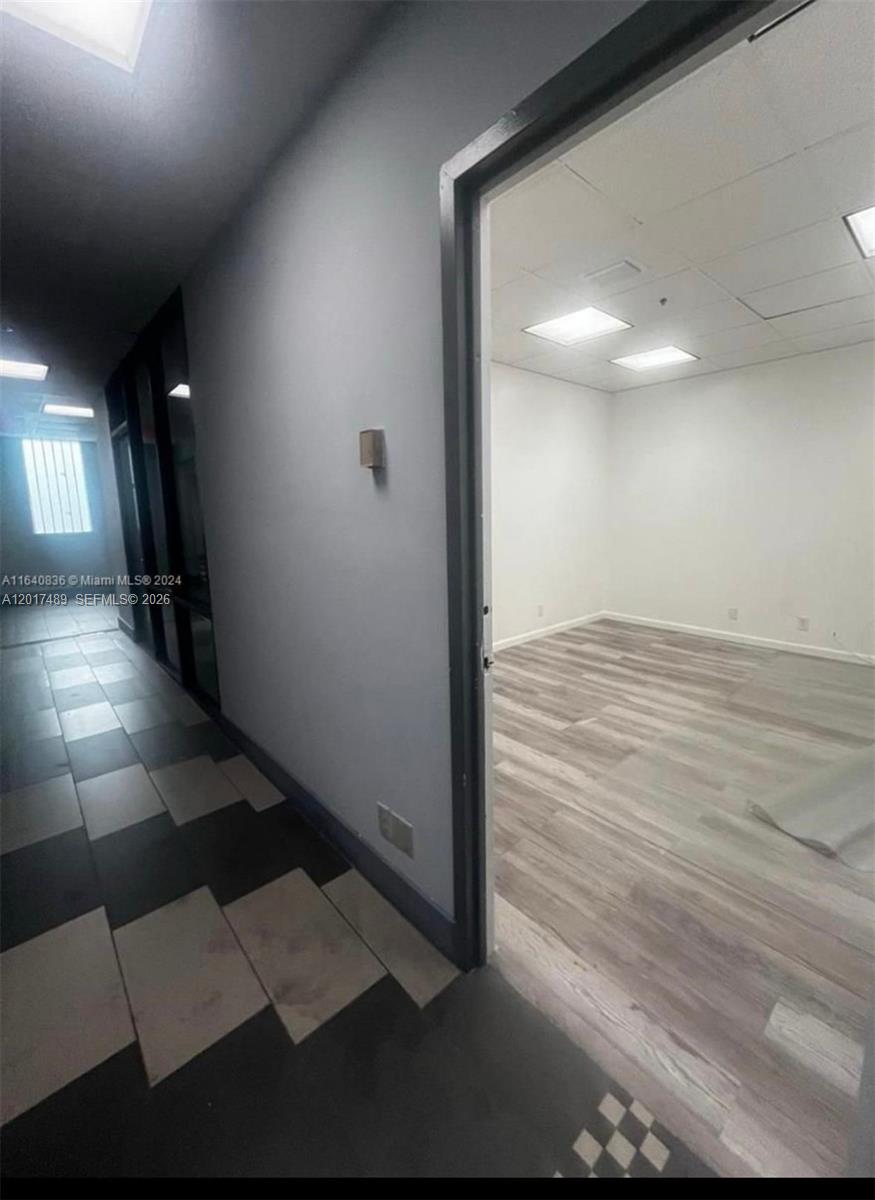 A hallway with patterned tile flooring leads to an open office space with wood-look flooring — 900 W 49th St Suite520, Hialeah FL 33012, HIALEAH, FL