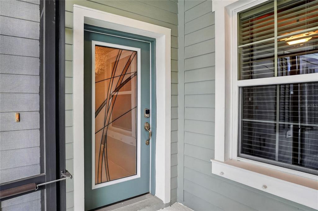 A teal front door with a decorative glass insert sits beside a window on a porch — 13531 CIRCA CROSSING DRIVE, LITHIA, FL