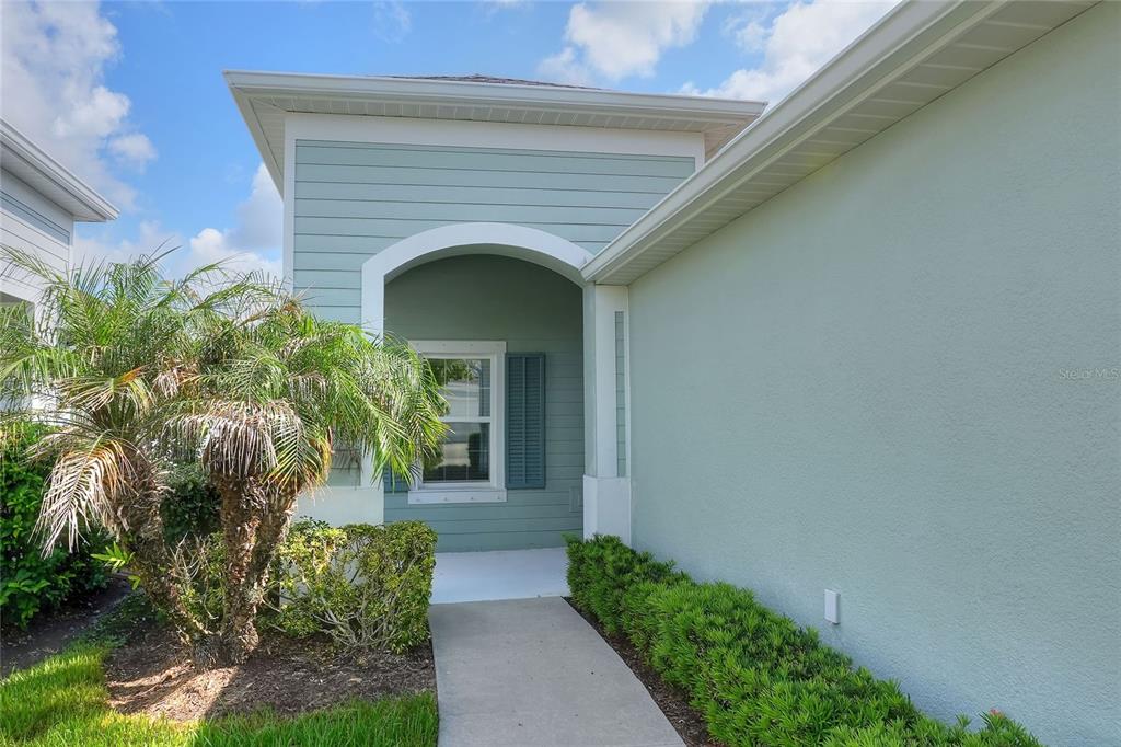 A concrete walkway leads to the recessed entryway of a light green house with siding — 13531 CIRCA CROSSING DRIVE, LITHIA, FL
