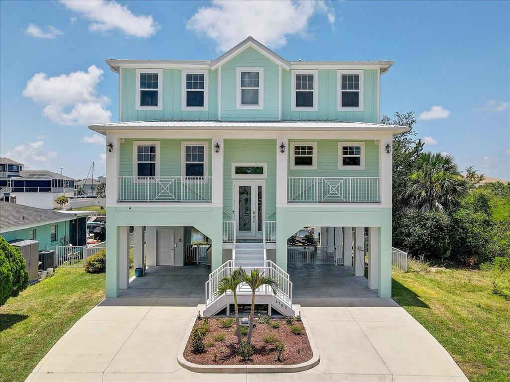 A light green, three-story stilt house with a front staircase and a concrete driveway — 4389 5TH ISLE DRIVE, HERNANDO BEACH, FL