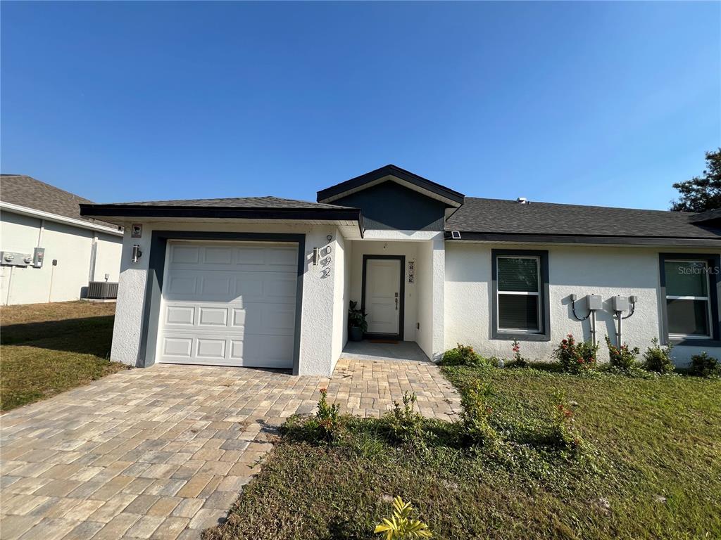 A single-story house with a white stucco exterior, a garage, and a paved walkway — 9092 AGATE STREET, PORT CHARLOTTE, FL