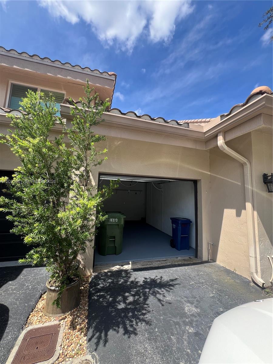 An open garage with a green trash bin and a blue recycling bin inside — 16373 Malibu Dr # 51, Weston FL 33326, WESTON, FL