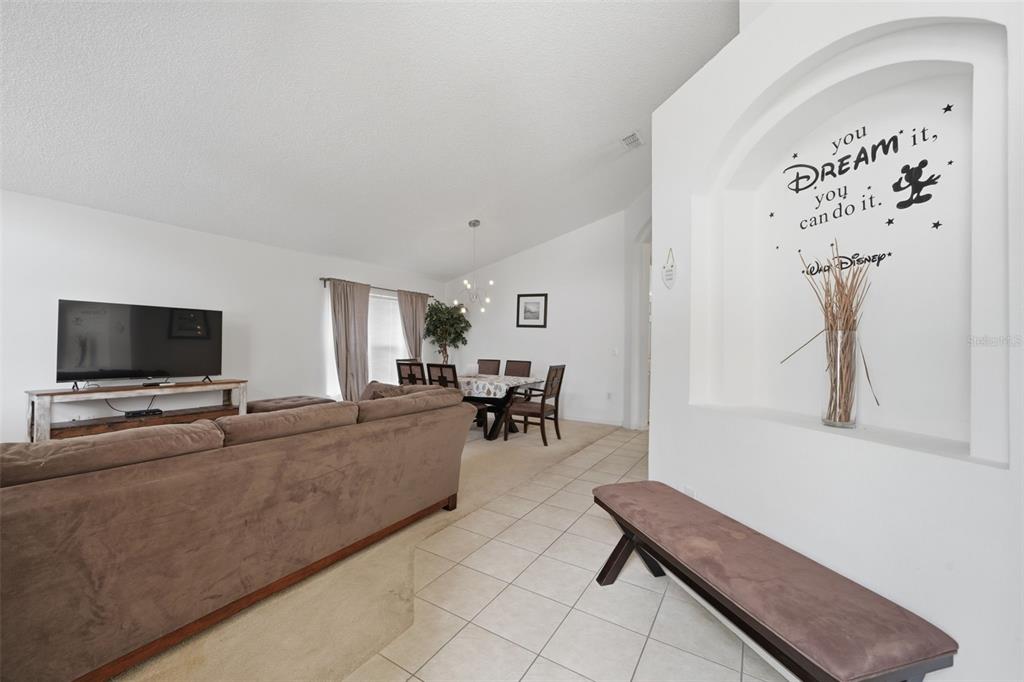 A living room with a brown sofa, television, dining area, and a decorative wall niche — 155 BAREFOOT BEACH WAY, KISSIMMEE, FL