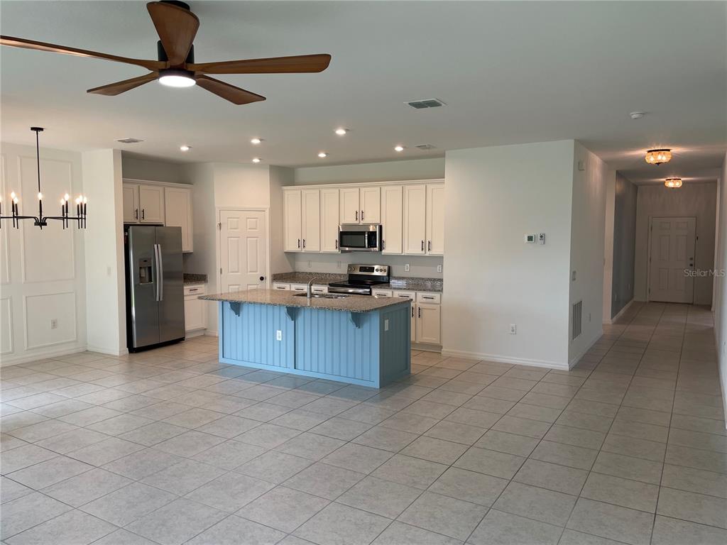 A kitchen features white cabinets, a blue island, stainless steel appliances, and tile flooring — 689 CROWN ROSE DRIVE, EAGLE LAKE, FL