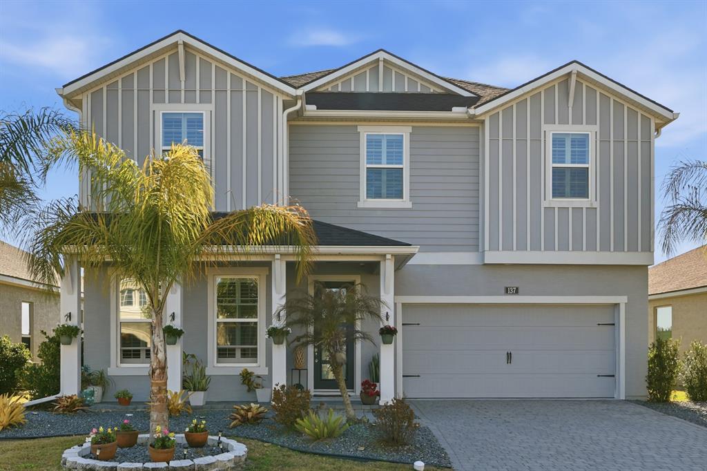 A two-story house with gray siding, a two-car garage, and a landscaped front yard — 137 AZURE MIST WAY, DAYTONA BEACH, FL