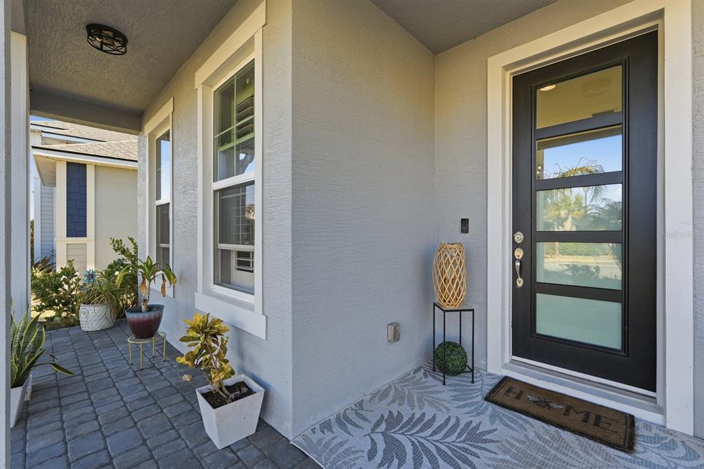 A front porch features a black door with glass panels, potted plants, and a rug — 137 AZURE MIST WAY, DAYTONA BEACH, FL