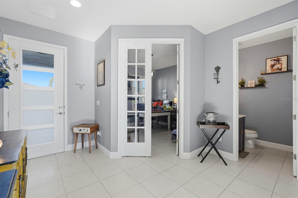 A bright entryway features light gray walls, tile flooring, a glass-paneled front door, and French doors — 137 AZURE MIST WAY, DAYTONA BEACH, FL