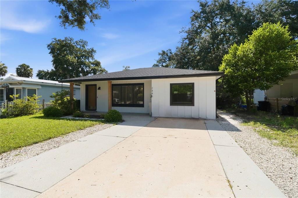 A single-story house with white vertical siding, a dark roof, and a concrete driveway — 2445 SANFORD AVENUE, SANFORD, FL
