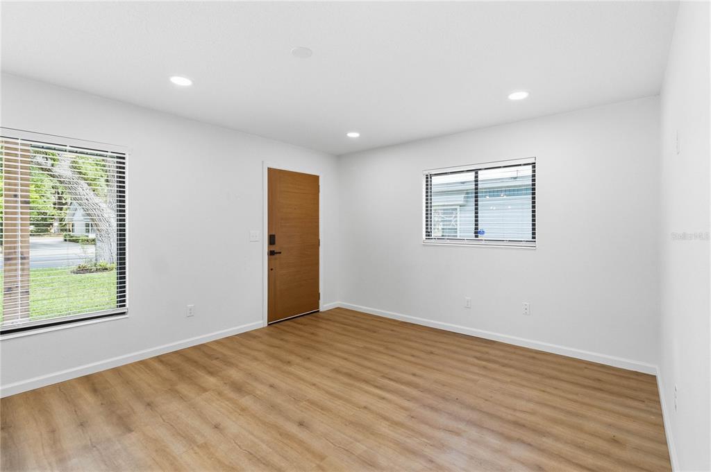 A living room features a brown leather sofa, two white armchairs, and light wood flooring — 2445 SANFORD AVENUE, SANFORD, FL