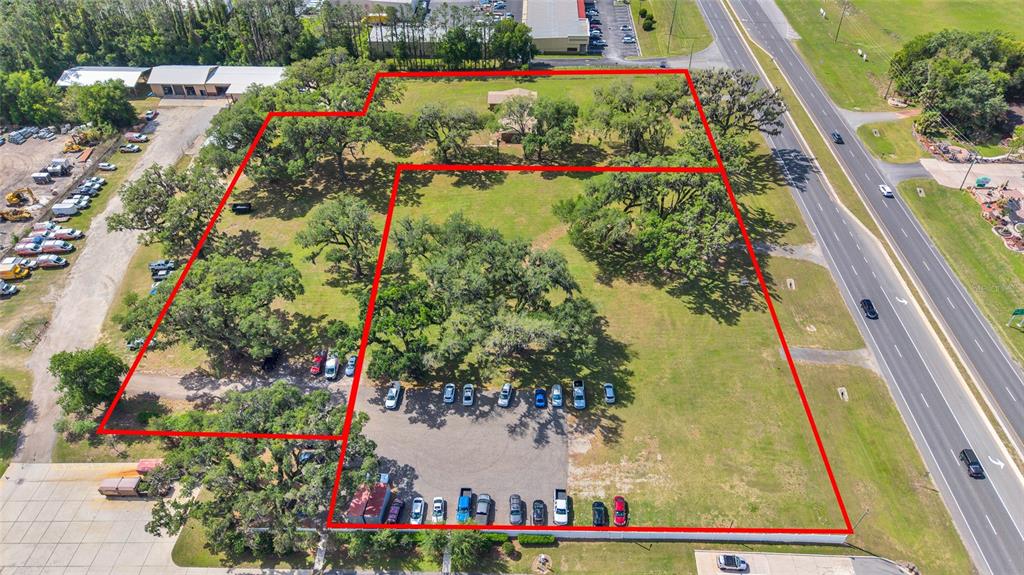 An aerial view shows a large, grassy lot with mature trees and parking areas — 9935 N US HIGHWAY 301, WILDWOOD, FL