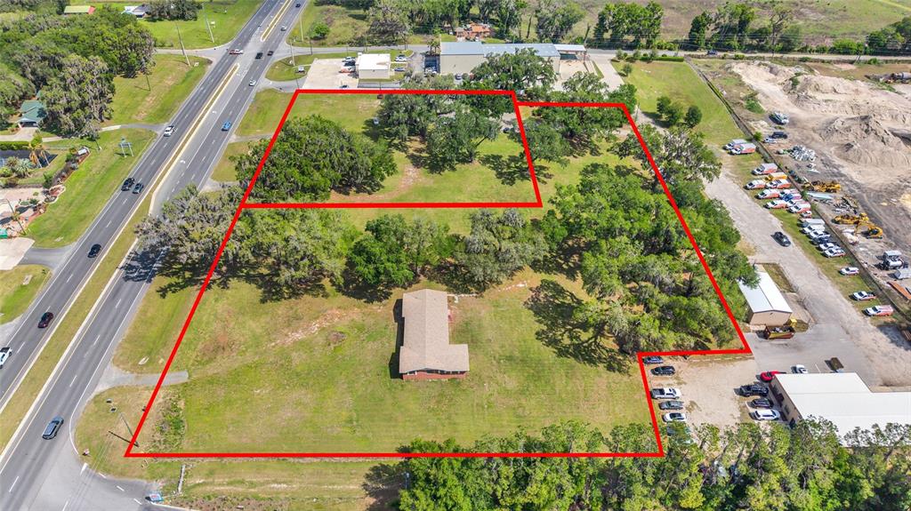 An aerial view shows a large, grassy lot with a house and trees outlined in red — 9935 N US HIGHWAY 301, WILDWOOD, FL