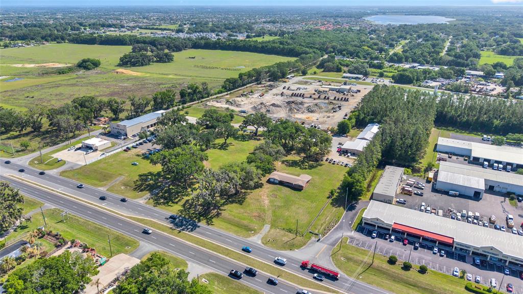 An aerial view shows a commercial property with buildings, parking lots, and surrounding green space — 9935 N US HIGHWAY 301, WILDWOOD, FL