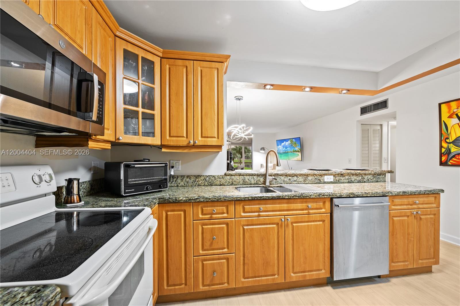 A kitchen features light wood cabinets, granite countertops, and stainless steel appliances — 424 SE 10th St # 104, Dania Beach FL 33004, DANIA BEACH, FL