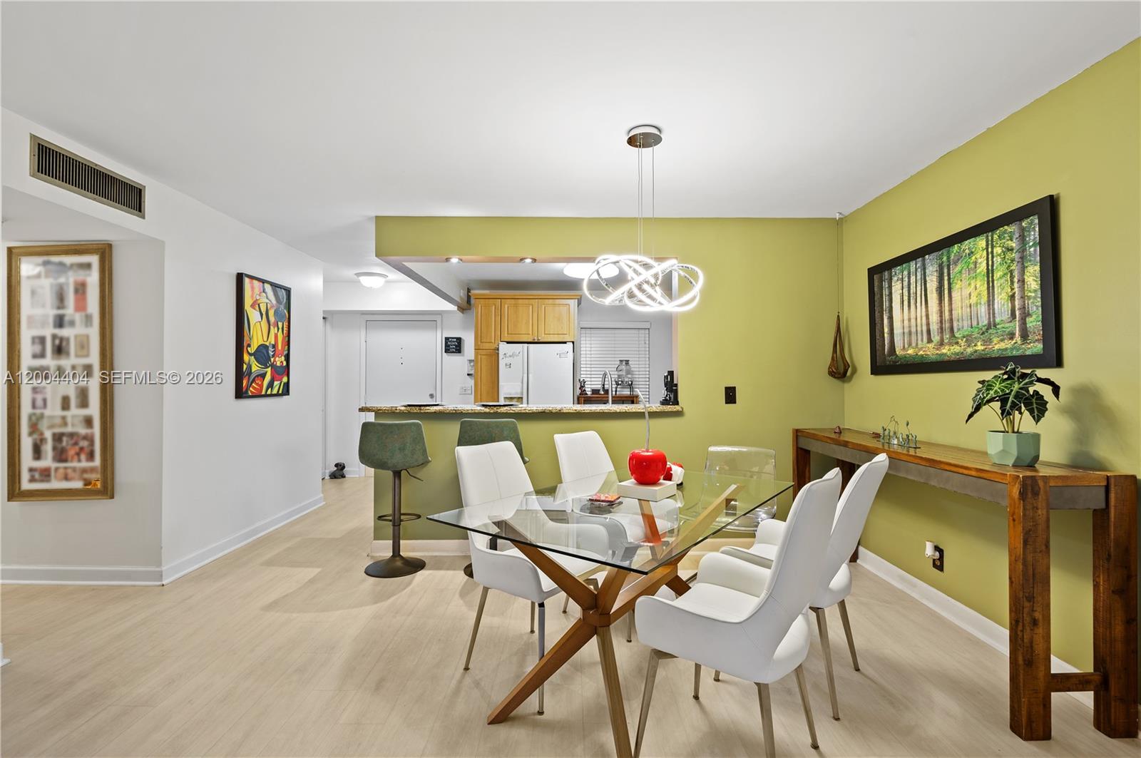 A dining area features a glass table, white chairs, and a green accent wall — 424 SE 10th St # 104, Dania Beach FL 33004, DANIA BEACH, FL