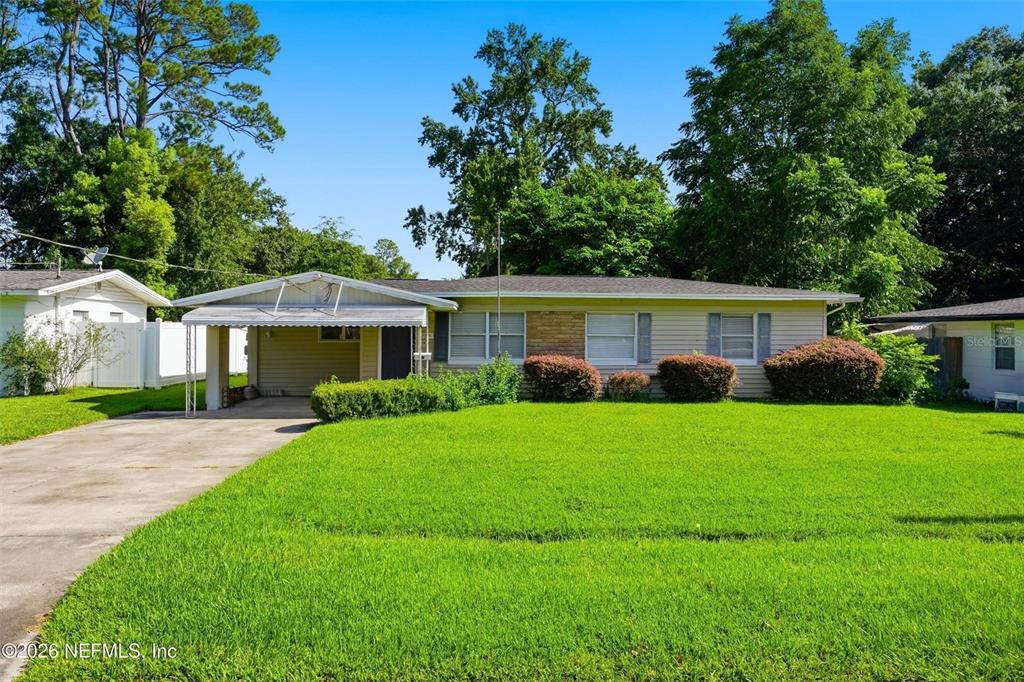 A single-story house with a carport, light siding, and a large front lawn — 5239 GLENWOOD AVENUE, JACKSONVILLE, FL